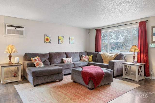 living room with a wall mounted AC, a textured ceiling, and hardwood / wood-style flooring