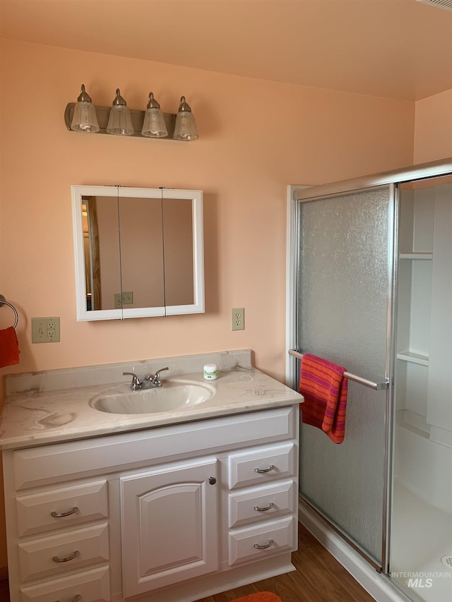 bathroom featuring vanity, a shower with shower door, and wood-type flooring