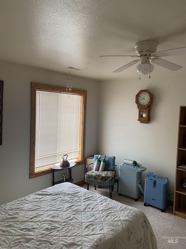 carpeted bedroom with ceiling fan and a textured ceiling