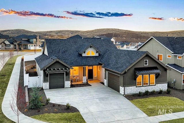 view of front of home featuring fence, driveway, stone siding, an attached garage, and a gate