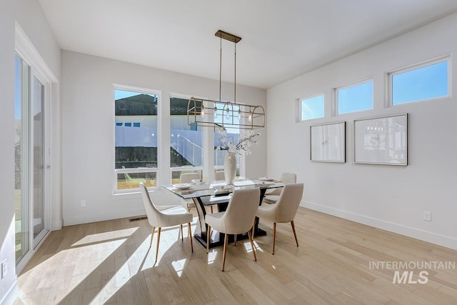 dining room with a chandelier, light wood finished floors, and baseboards