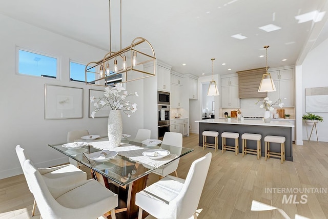 dining area with an inviting chandelier, light wood-style flooring, recessed lighting, and baseboards