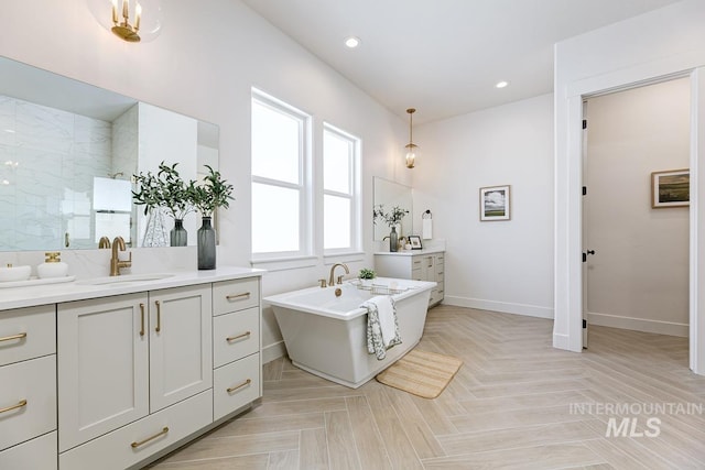 full bath with two vanities, recessed lighting, a freestanding bath, a sink, and walk in shower