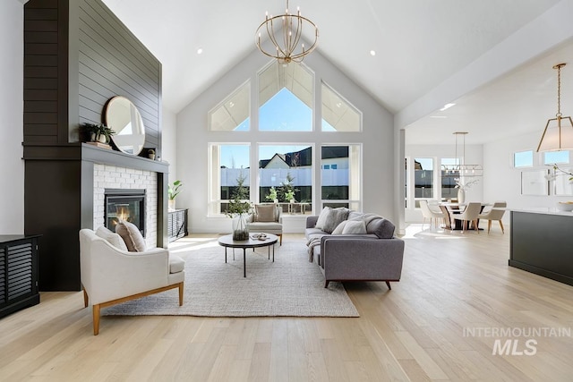 living area featuring a fireplace, high vaulted ceiling, an inviting chandelier, and wood finished floors