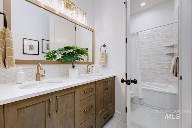 bathroom featuring double vanity, backsplash, toilet, and a sink