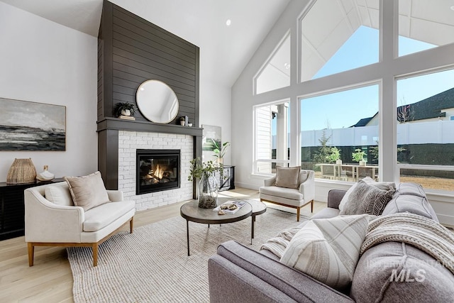 living room featuring a fireplace, wood finished floors, baseboards, and high vaulted ceiling