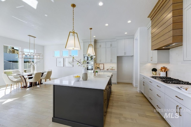 kitchen featuring light countertops, stainless steel gas stovetop, light wood-style floors, and a sink