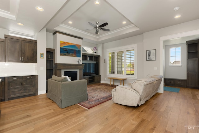 6178 N Bolsena Ln, Meridian, ID 83646 - living room with light wood finished floors, a ceiling fan, a fireplace, a tray ceiling, and recessed lighting