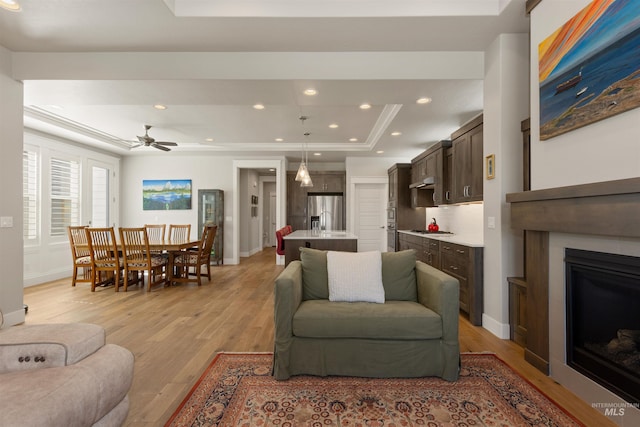 6178 N Bolsena Ln, Meridian, ID 83646 - living area featuring a tray ceiling, light wood finished floors, a fireplace, baseboards, and recessed lighting