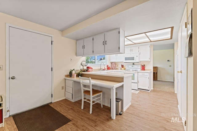 kitchen with kitchen peninsula, white cabinets, a kitchen breakfast bar, light wood-type flooring, and white appliances