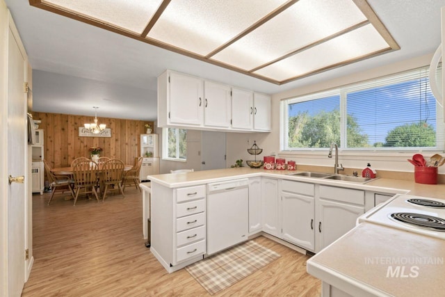 kitchen with wood walls, sink, white dishwasher, kitchen peninsula, and pendant lighting