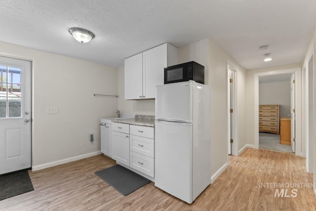 kitchen featuring white cabinetry, a textured ceiling, light wood-type flooring, and white refrigerator