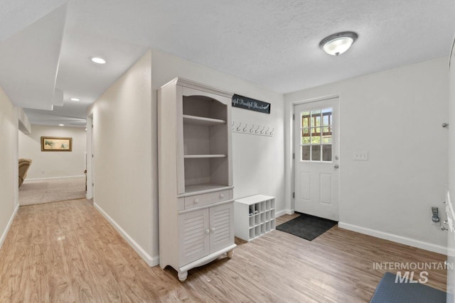 corridor featuring a textured ceiling and light wood-type flooring