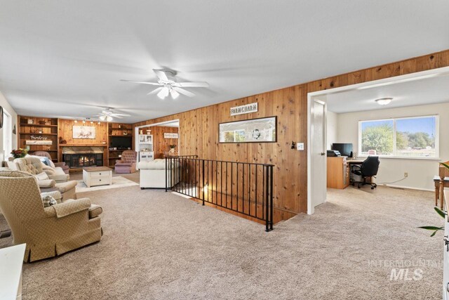 living room with ceiling fan, carpet flooring, and wooden walls