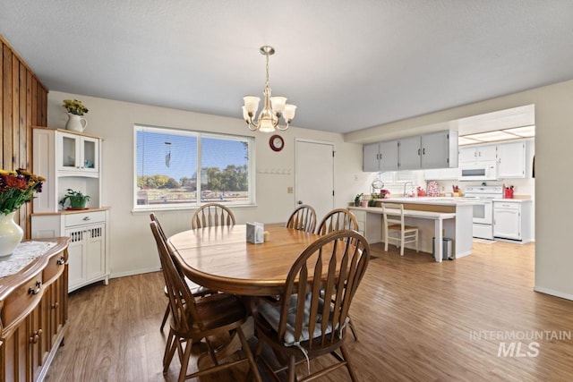 dining room with a notable chandelier, hardwood / wood-style floors, and a textured ceiling