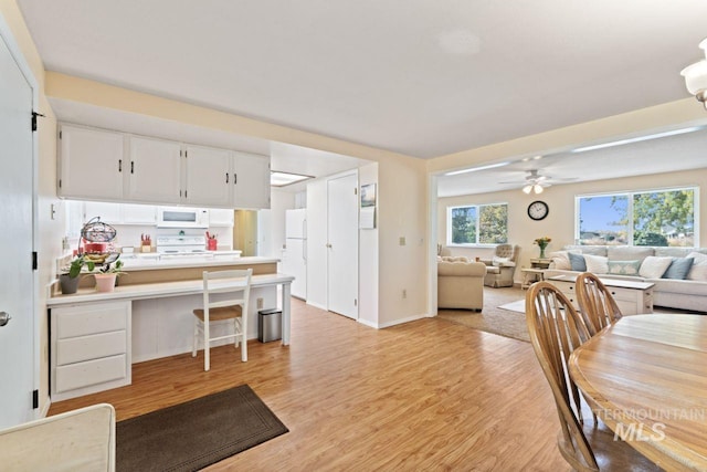 dining area featuring built in desk, light wood-type flooring, and ceiling fan