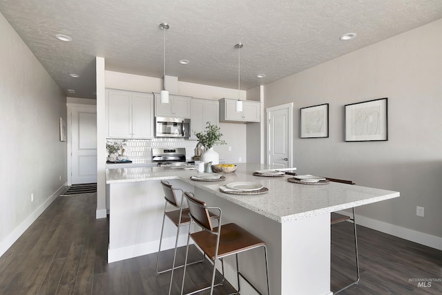 1694 N Solterra Ln, Meridian, ID 83646 - kitchen featuring recessed lighting, a textured ceiling, a kitchen bar, dark wood finished floors, and appliances with stainless steel finishes