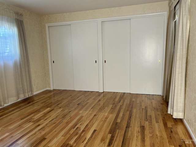 unfurnished bedroom featuring multiple closets and wood finished floors