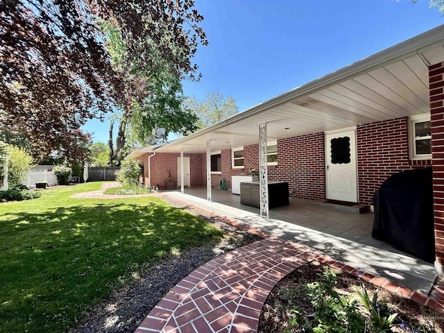 exterior space with fence, a lawn, a patio area, and brick siding