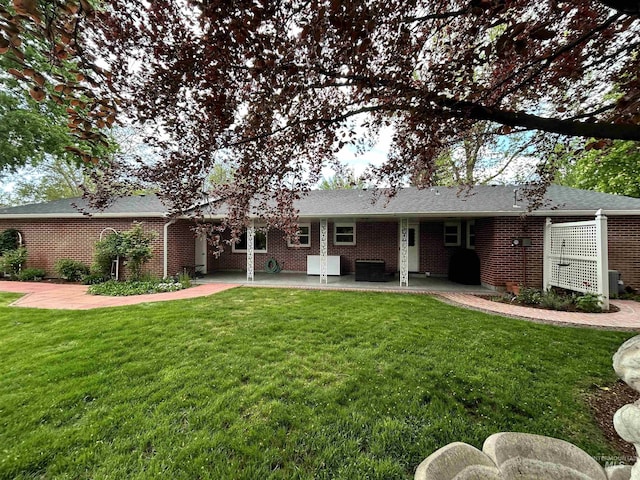 rear view of house with a lawn, brick siding, and a patio area