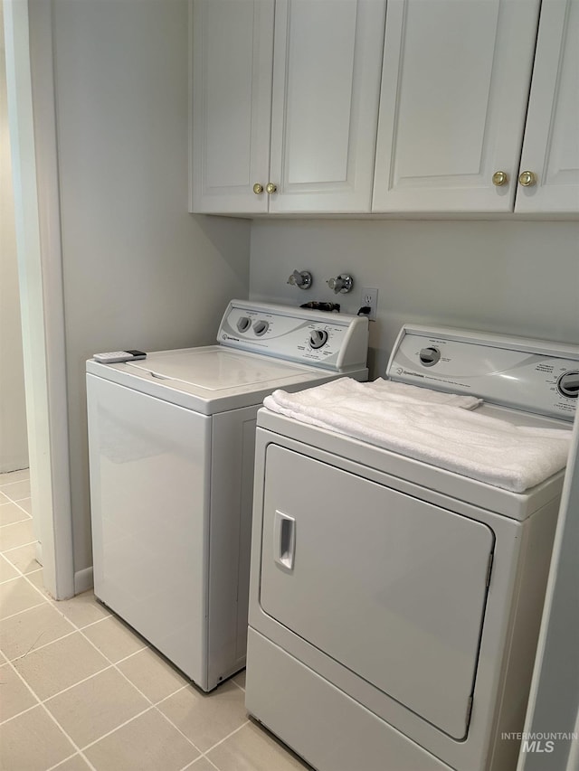 laundry area featuring cabinet space, light tile patterned flooring, and washer and dryer