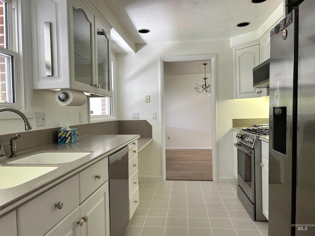 kitchen with a sink, white cabinetry, light tile patterned flooring, and stainless steel appliances