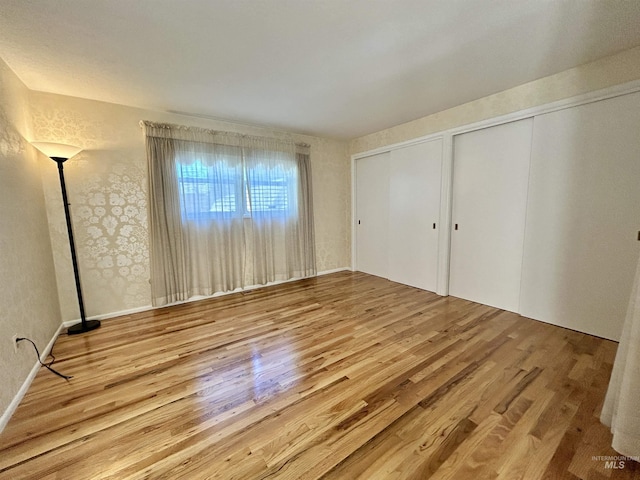 unfurnished bedroom with multiple closets and wood finished floors