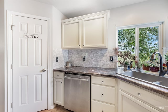 kitchen with white cabinets, light hardwood / wood-style flooring, backsplash, sink, and stainless steel dishwasher