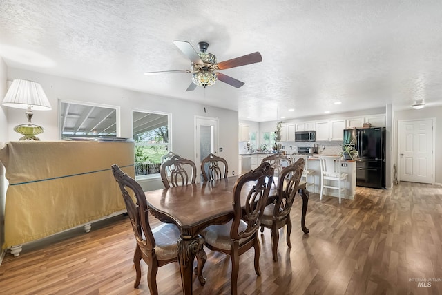 dining space with ceiling fan, a textured ceiling, and light wood-type flooring