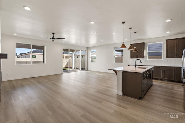 kitchen featuring open floor plan, a center island with sink, and light countertops