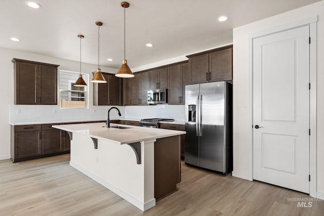 kitchen featuring dark brown cabinetry, a kitchen breakfast bar, appliances with stainless steel finishes, and a sink