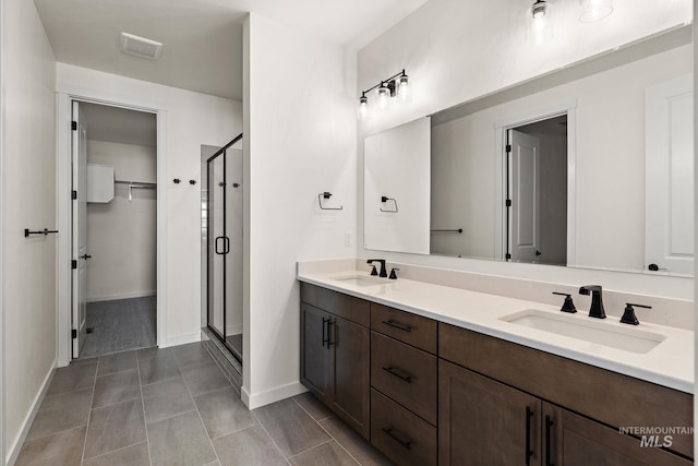 bathroom featuring double vanity, visible vents, a shower stall, and a sink