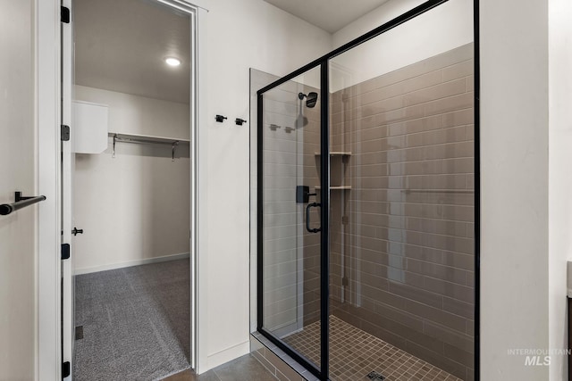 full bathroom featuring baseboards, a spacious closet, and a shower stall