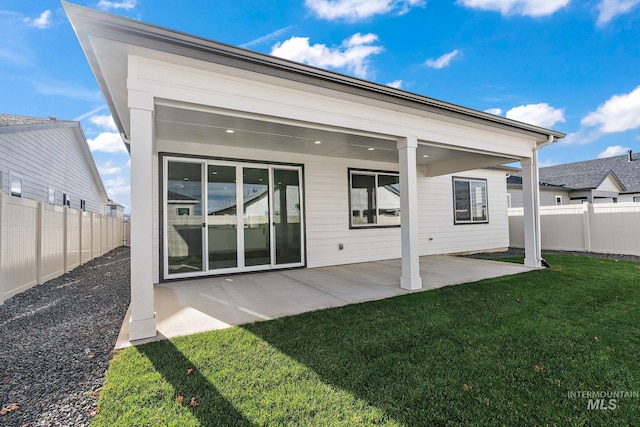 rear view of house with a lawn, a fenced backyard, and a patio area