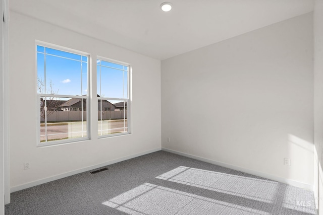 empty room featuring visible vents, baseboards, and carpet