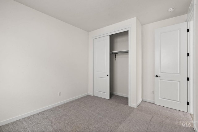 unfurnished bedroom featuring a closet, baseboards, and carpet flooring