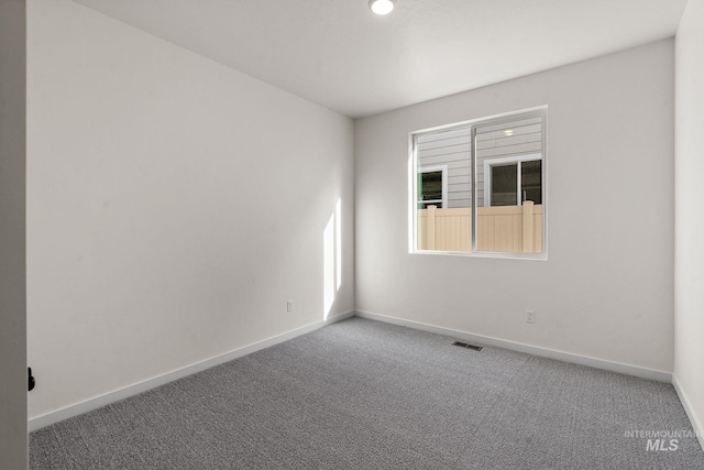 carpeted spare room with visible vents and baseboards