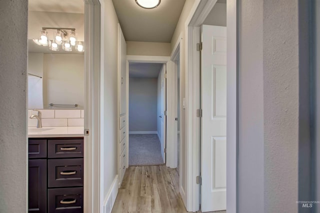 hallway with sink and light wood-type flooring