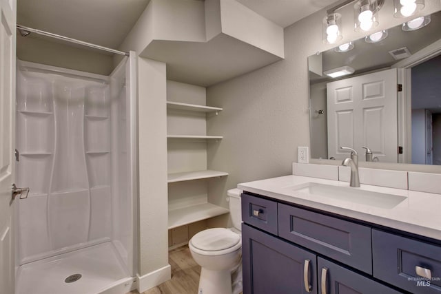 bathroom with vanity, hardwood / wood-style floors, walk in shower, and toilet