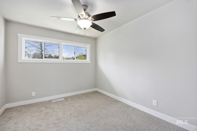empty room featuring ceiling fan, carpet, baseboards, and visible vents