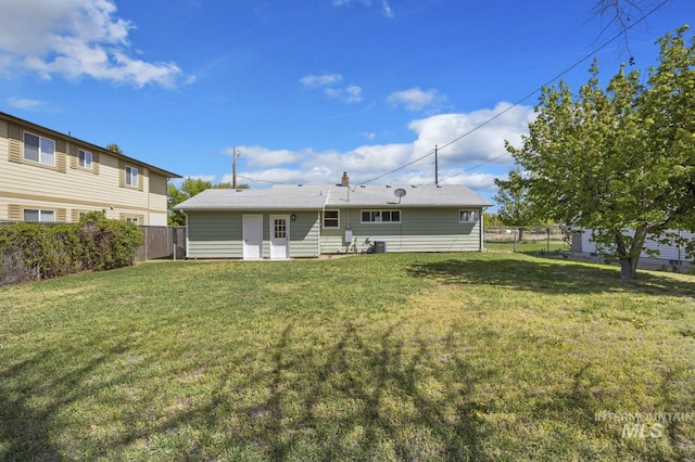 rear view of property with a yard, central AC, and a fenced backyard