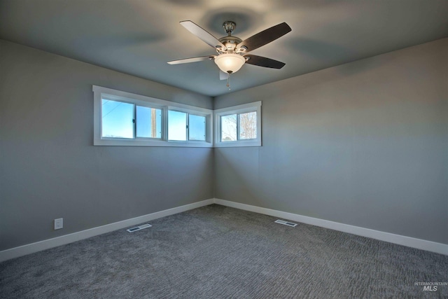 spare room featuring dark colored carpet and ceiling fan