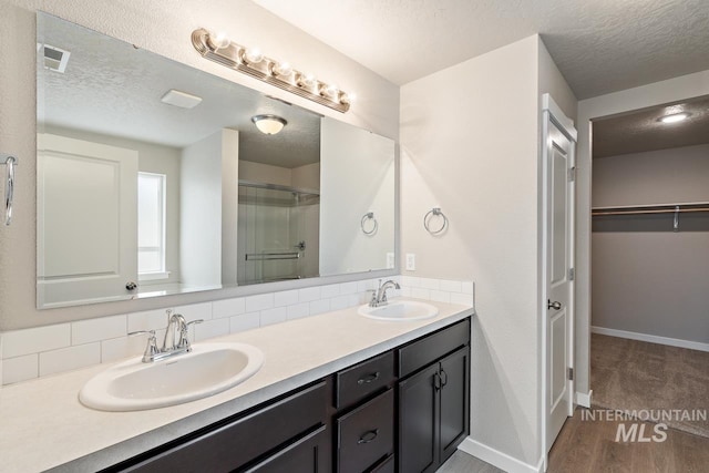 19257 Red Eagle Way, Caldwell, ID 83605 - full bathroom with a textured ceiling, a stall shower, baseboards, double vanity, and a walk in closet
