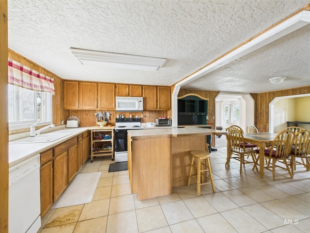 1334 Morehouse Rd, Emmett, ID 83617 - kitchen with white appliances, a sink, a textured ceiling, a kitchen island, and wooden walls