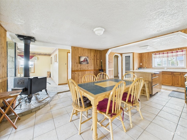 1334 Morehouse Rd, Emmett, ID 83617 - dining space featuring a wood stove, wooden walls, light tile patterned floors, and a textured ceiling