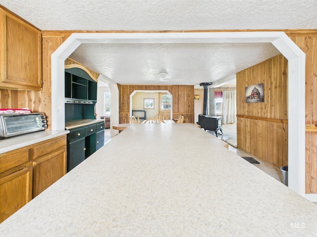 1334 Morehouse Rd, Emmett, ID 83617 - kitchen featuring wood walls, a wood stove, light countertops, a textured ceiling, and brown cabinetry