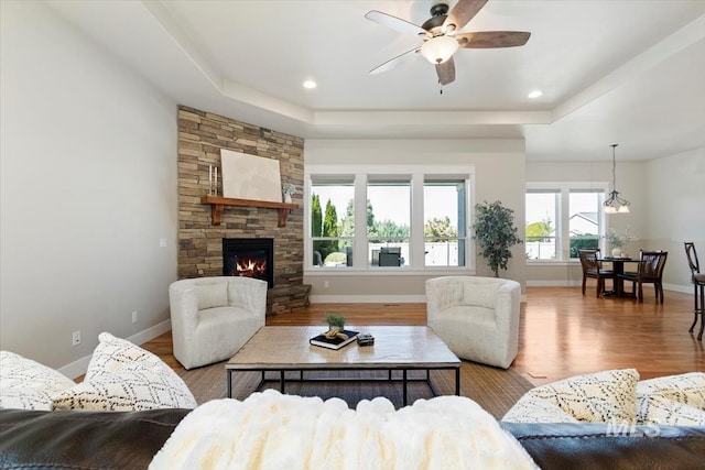 living room featuring wood finished floors, a ceiling fan, a tray ceiling, baseboards, and recessed lighting
