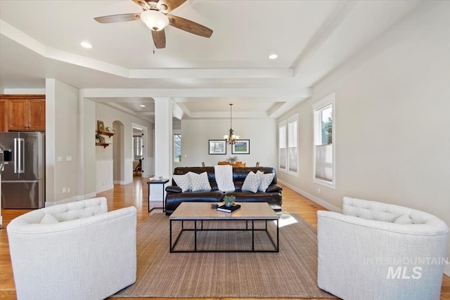 living room featuring light wood-style floors, a raised ceiling, ornate columns, ceiling fan, and recessed lighting