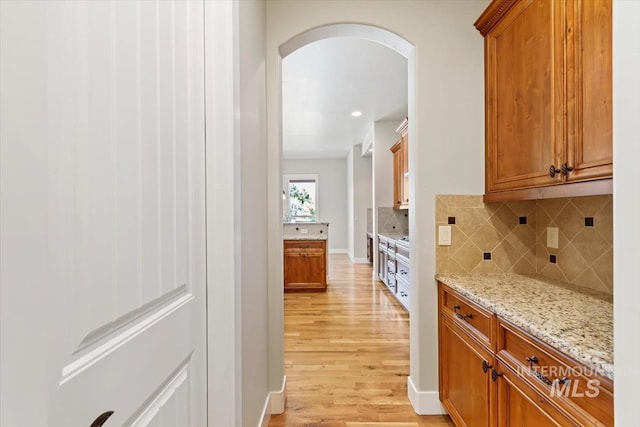 corridor with arched walkways and light wood finished floors