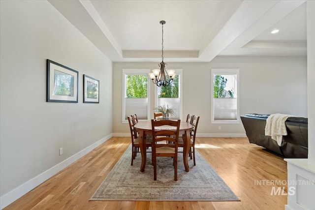 dining room featuring a tray ceiling, a chandelier, baseboards, and light wood-type flooring